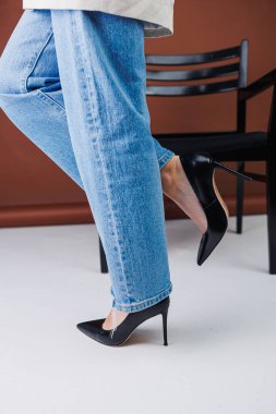 Kot pantolon ve siyah deri topuklular içinde güzel kadın bacakları. Kadın kış ayakkabıları.