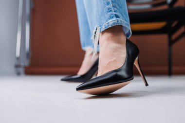 Kot pantolon ve siyah deri topuklular içinde güzel kadın bacakları. Kadın kış ayakkabıları.