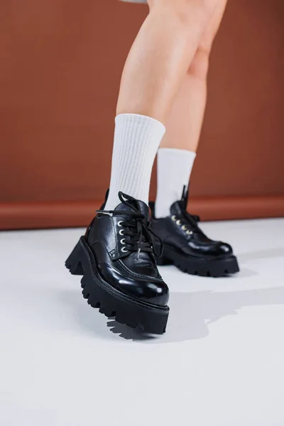 Beautiful female legs in black leather lace-up loafers. Female legs with fashionable shoes and white socks. Casual black women\'s shoes
