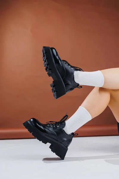 Beautiful female legs in black leather lace-up loafers. Female legs with fashionable shoes and white socks. Casual black women's shoes