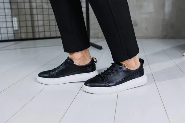 Modern men\'s shoes. Male legs in black pants and black casual sneakers. Men\'s fashionable shoes