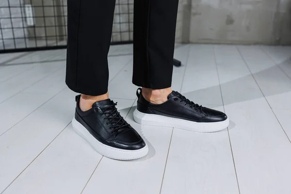 Modern men's shoes. Male legs in black pants and black casual sneakers. Men's fashionable shoes