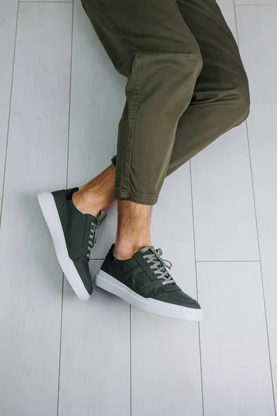 Male legs in pants and green casual sneakers. Men\'s fashionable shoes