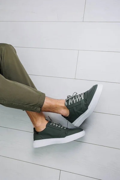 Male legs in pants and green casual sneakers. Men\'s fashionable shoes