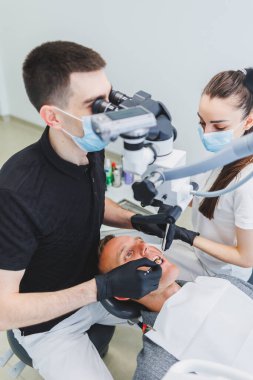 Hastaları tedavi etmek için mikroskobu olan modern bir diş kliniği. Bir dişçi hastanın dişlerini incelemek için mikroskop kullanır. Tıbbi ekipman, diş sağlığı kliniği.