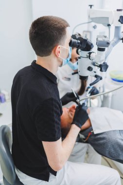 Hastaları tedavi etmek için mikroskobu olan modern bir diş kliniği. Bir dişçi hastanın dişlerini incelemek için mikroskop kullanır. Tıbbi ekipman, diş sağlığı kliniği.