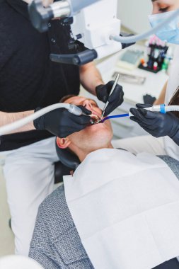 Hastaları tedavi etmek için mikroskobu olan modern bir diş kliniği. Bir dişçi hastanın dişlerini incelemek için mikroskop kullanır. Tıbbi ekipman, diş sağlığı kliniği.