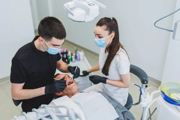 Dental office, examining a patient in a dental chair. Dental treatment is performed by a doctor and an assistant. Dental care.