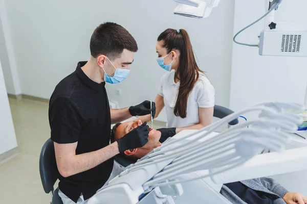 Dental office, examining a patient in a dental chair. Dental treatment is performed by a doctor and an assistant. Dental care.