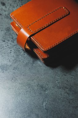 Gri bir arka planda el yapımı kahverengi deri erkek cüzdanı. Gerçek deriden yapılmış ürünler..