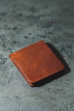 Gri bir arka planda el yapımı kahverengi deri erkek cüzdanı. Gerçek deriden yapılmış ürünler..