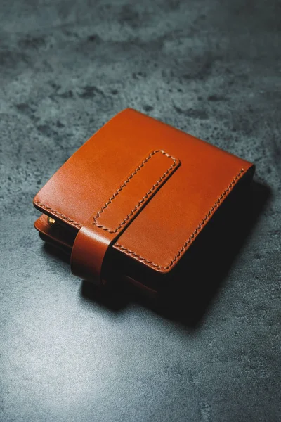 Stylish handmade brown leather men's wallet on a gray background. Product made of genuine leather.