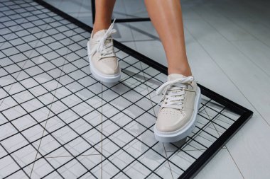 Female beautiful legs in beige casual sneakers. Women's stylish leather summer shoes