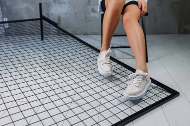 Female beautiful legs in beige casual sneakers. Women's stylish leather summer shoes