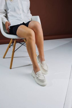 Women shoes. Close up of female legs in leather white loafers. New spring-summer collection of women's leather shoes