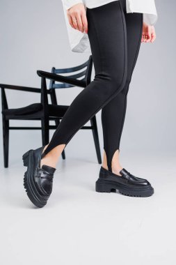 Women shoes. Close-up of female legs in black leggings and black leather loafers. New spring-summer collection of women's leather shoes
