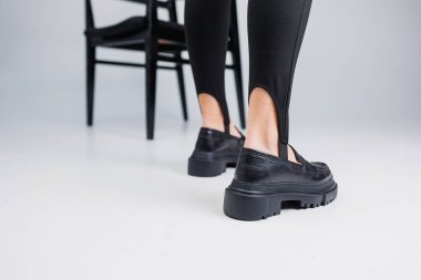 Women shoes. Close-up of female legs in black leggings and black leather loafers. New spring-summer collection of women's leather shoes