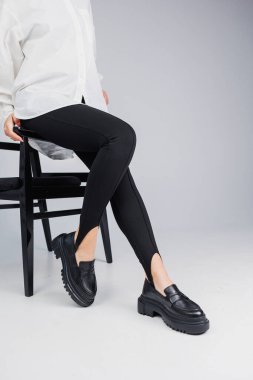 Close-up of slender female legs in black leggings and black leather loafers. New spring-summer collection of women's leather shoes