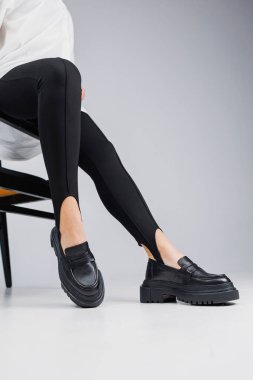 Close-up of slender female legs in black leggings and black leather loafers. New spring-summer collection of women's leather shoes