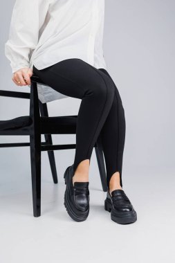 Close-up of slender female legs in black leggings and black leather loafers. New spring-summer collection of women's leather shoes