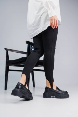 Close-up of slender female legs in black leggings and black leather loafers. New spring-summer collection of women's leather shoes