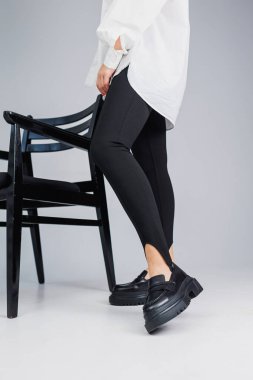 Close-up of slender female legs in black leggings and black leather loafers. New spring-summer collection of women's leather shoes
