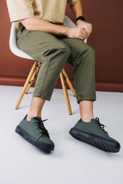 Summer shoes. Close-up of male legs in green pants and green casual sneakers. Summer leather men's shoes