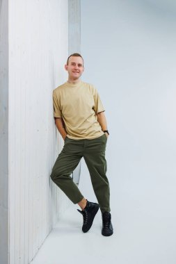 A young handsome man in casual clothes poses on a white background in the studio