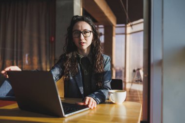 Top view of experienced woman in glasses working with laptop in coworking space, young freelancer working remotely with ideas for blog website