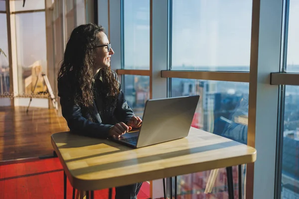 Top view of experienced woman in glasses working with laptop in coworking space, young freelancer working remotely with ideas for blog website