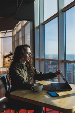 Top view of experienced woman in glasses working with laptop in coworking space, young freelancer working remotely with ideas for blog website
