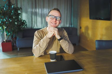 Top view of man in casual clothes with coffee sitting at workplace using netbook while working during working day. A successful businessman works on a laptop computer