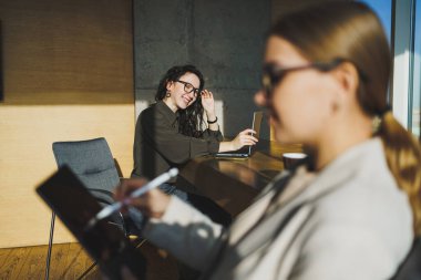 Smiling positive diverse colleagues in casual clothes working on a new project sitting together at the negotiation table during a meeting in a bright creative workspace