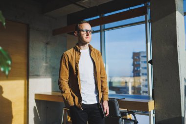 Young smart freelancer in casual clothes and glasses working on tablet working with documents and laptop computer at table. A student studying online with a netbook