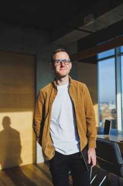 Young smart freelancer in casual clothes and glasses working on tablet working with documents and laptop computer at table. A student studying online with a netbook