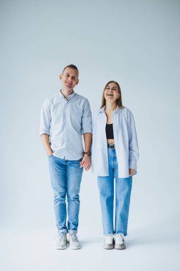 İlişki konsepti. Beyaz gömlekli ve kot pantolonlu mutlu bir çiftin fotoğrafı. Mutlu genç çift