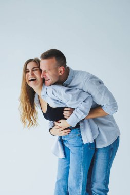 Beyaz gömlekli, kot pantolonlu, izole beyaz arka planda mutlu bir çiftin fotoğrafı. Bir erkek ve bir kadın beyaz bir arka planda sarılıyorlar.