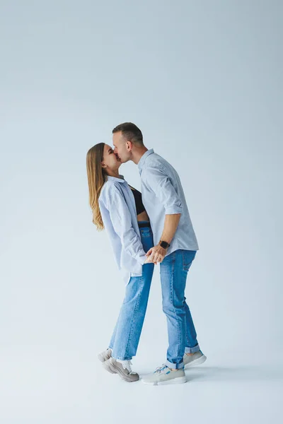 Photo of happy couple wearing white shirts, blue jeans, isolated white background. A man and a woman are hugging on a white background
