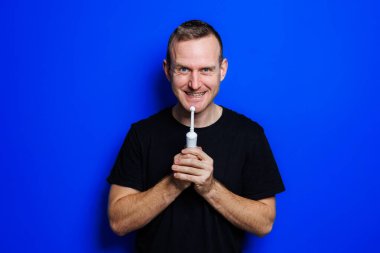 Portrait of a young handsome man brushing his teeth with an ultrasonic modern toothbrush. Oral care. Morning self care