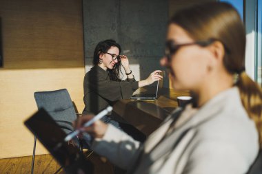 Smiling positive diverse colleagues in casual clothes working on a new project sitting together at the negotiation table during a meeting in a bright creative workspace