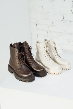 Stylish women's leather brown boots on white background, women's spring shoes close-up. Fashionable boots for women. Selective focus