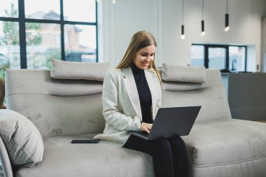 Woman cheerful charming person sitting behind a netbook watching having a good mood working at home indoors. Remote freelance work