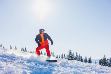 A snowboarder walks down a snowy slope in winter on the snow. Snowboarding, winter freeride