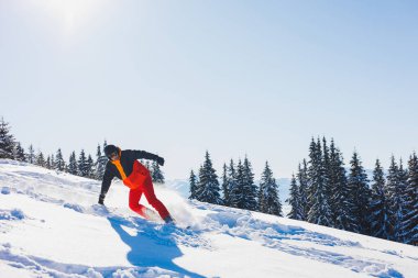 A snowboarder walks down a snowy slope in winter on the snow. Snowboarding, winter freeride