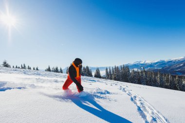 A snowboarder walks down a snowy slope in winter on the snow. Snowboarding, winter freeride