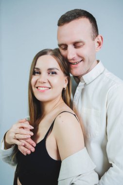 Beautiful young couple in love hugging on a white background. A stylish couple embraces and enjoys feelings. Men and women in stylish casual clothes