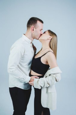 Beautiful young couple in love hugging on a white background. A stylish couple embraces and enjoys feelings. Men and women in stylish casual clothes