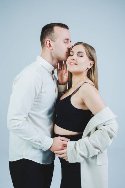 Beautiful young couple in love hugging on a white background. A stylish couple embraces and enjoys feelings. Men and women in stylish casual clothes