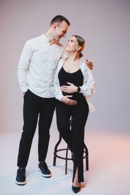 Young couple in love in white shirts hugging on a white background. A happy married couple looks lovingly into each other's eyes. The concept of healthy family relationships