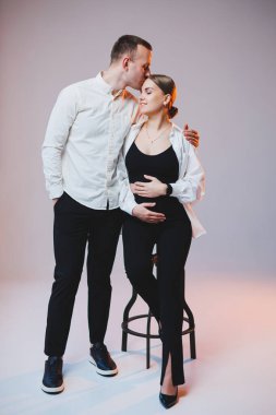 Young couple in love in white shirts hugging on a white background. A happy married couple looks lovingly into each other's eyes. The concept of healthy family relationships